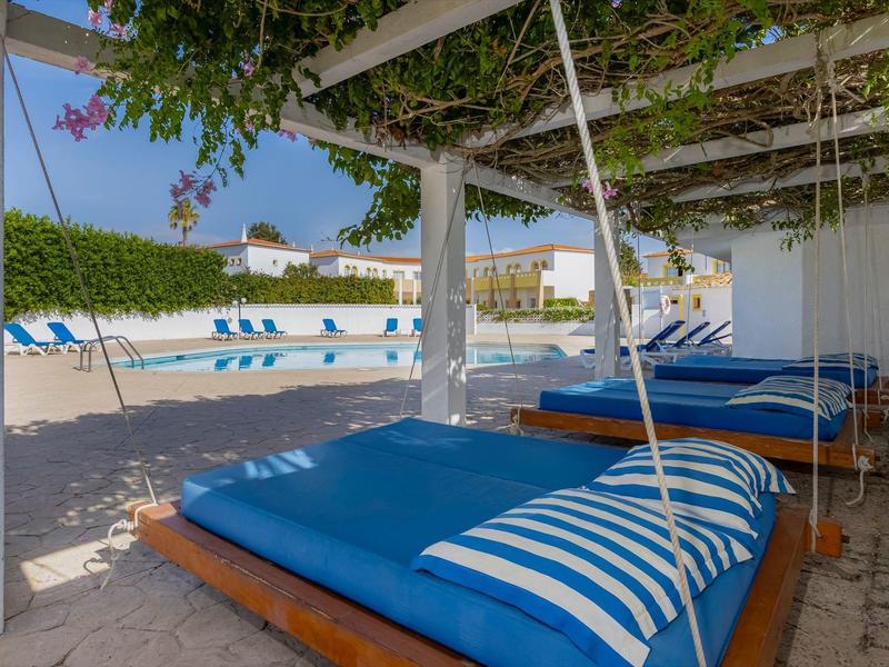 Gemütliche blaue Liegebetten unter einem schattigen Pavillon am Strand mit Meerblick.