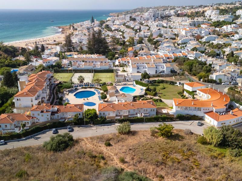 Luftaufnahme eines Hotels am Strand mit Pools und umliegenden Wohngebäuden.