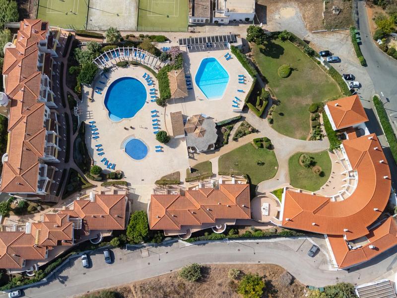 Luftaufnahme eines Hotelkomplexes mit mehreren Gebäuden, Poolbereich und Gartenanlagen.