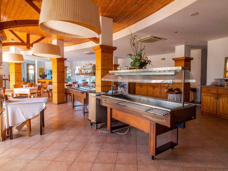 Großer, heller Speisesaal mit Holzbalken, verzierten Deckenlampen und gedeckten Tischen.