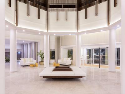 Area lobby di hotel luminosa e moderna con pavimenti in marmo bianco e zone salotto.