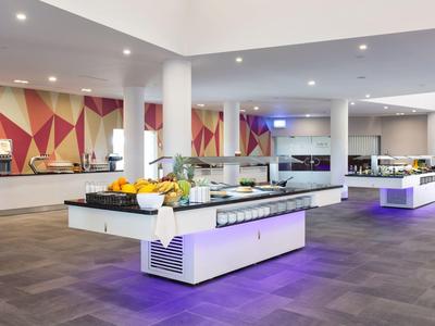 Sala da pranzo moderna in hotel con buffet, pareti chiare e decorazioni geometriche alle pareti.