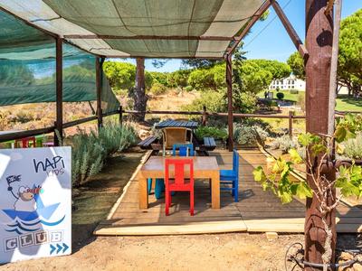 Cozy outdoor area with colorful chairs and plants under a shaded canopy.
