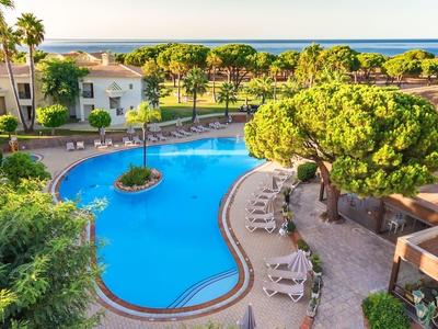 Piscina dell'hotel con lettini circostanti e vista sul mare al tramonto.