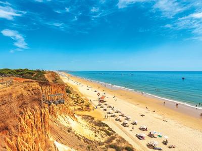 Vasta spiaggia con scogliere chiare, cielo blu e ombrelloni sul mare
