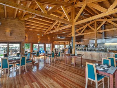 Ampia sala da pranzo luminosa con soffitto in legno, pavimento in legno e sedie blu in un hotel.