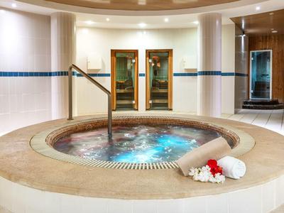 Vasca idromassaggio rotonda con corrimano e asciugamani accanto a fiori in un'area spa.