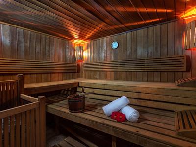 Interno di una sauna in legno con panche, asciugamani e un secchio.