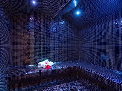 Stanza del vapore scura con piastrelle a mosaico blu e asciugamani sulla panca.