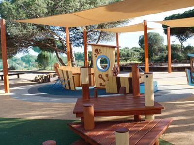 Parco giochi per bambini con strutture in legno e aree ombreggiate all'aperto