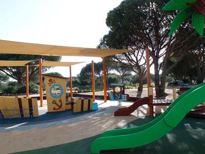 Parco giochi per bambini con aree verdi, alberi e attrezzature da gioco all'aperto.