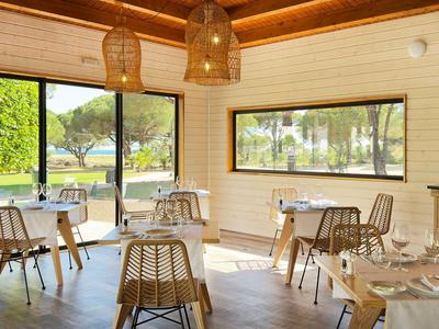Heller Innenraum eines Restaurants mit Holzwänden und Blick auf Terrasse und grünen Garten.