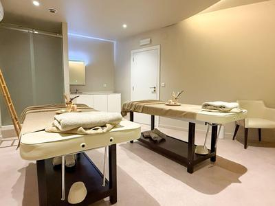 Helles Therapie- oder Massageraum mit zwei Massagetischen und gedämpftem Licht.