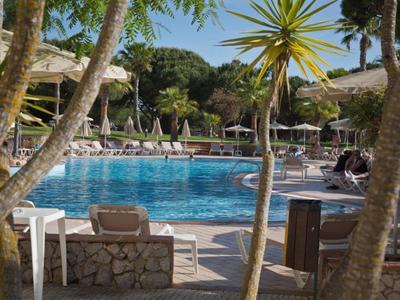 Area piscina con lettini e ombrelloni in un hotel tropicale.