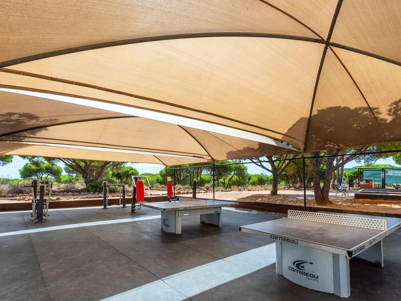 Area esterna coperta con tavolo da ping pong e panchina nel giardino dell'hotel.