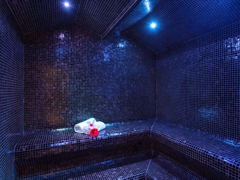 Stanza del vapore scura con piastrelle a mosaico blu e asciugamani sulla panca.