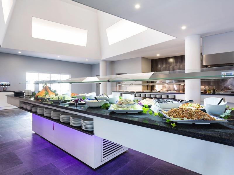 Buffet moderno con una varietà di piatti in una stanza luminosa e spaziosa con soffitti alti.