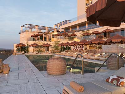 Moderner Hotelpoolbereich mit Sonnenliegen, Sonnenschirmen und einem Blick auf den Sonnenuntergang.