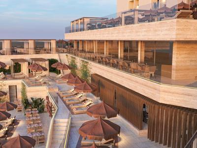 Terrasse mit Liegestühlen und Sonnenschirmen neben einem Hotelgebäude im warmen Licht.