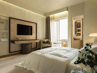 Helles Hotelzimmer mit gemütlichem Bett, Fernseher, Sessel und Sitzbereich am Fenster.