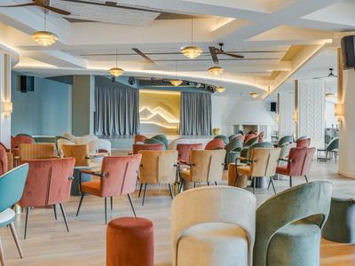 Area lounge dell'hotel moderna con sedie colorate e grandi finestre