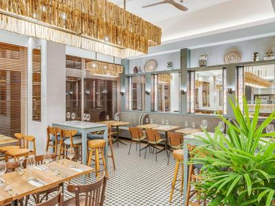 Ristorante luminoso con mobili in legno, pavimento decorato e grandi finestre che si affacciano sulla terrazza.