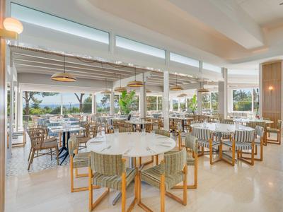 Ristorante luminoso con mobili moderni e grandi finestre, vista su terrazza e giardino.