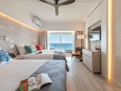 Camera d'hotel moderna con due letti, vista mare e design minimalista.