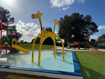 Area giochi colorata per bambini con piscina per schizzi e scivolo a forma di giraffa all'aperto.