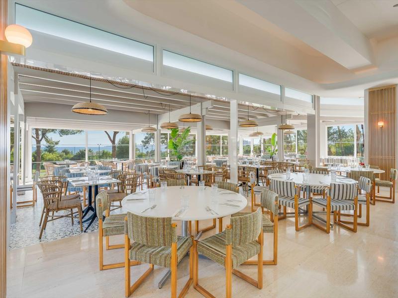 Ristorante luminoso con mobili moderni e grandi finestre, vista su terrazza e giardino.