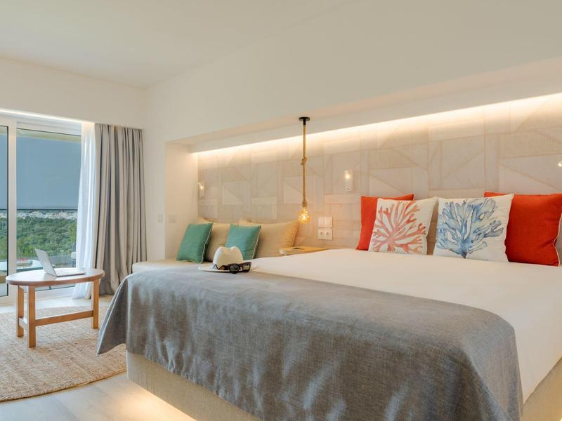 Elegante ristorante dell'hotel con sedie verdi imbottite e tavoli bianchi sotto luci moderne.