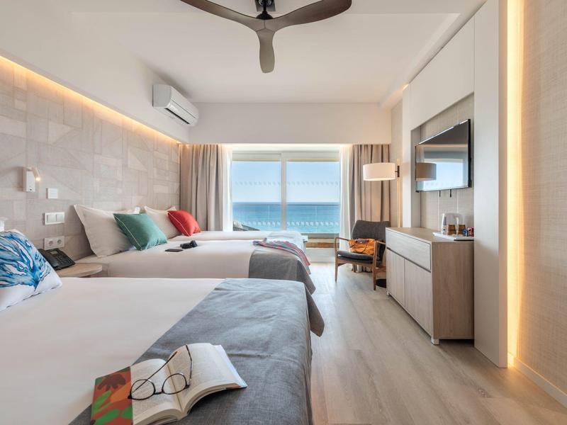 Camera d'hotel moderna con due letti, vista mare e design minimalista.