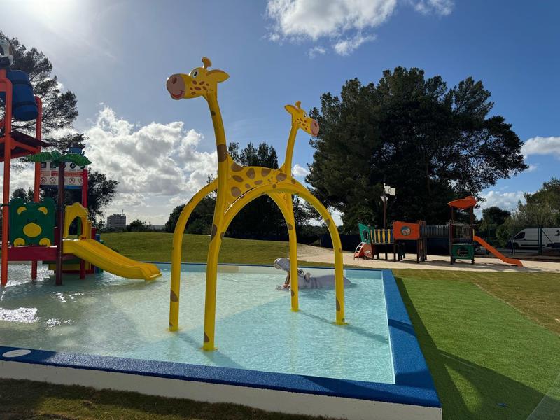 Area giochi colorata per bambini con piscina per schizzi e scivolo a forma di giraffa all'aperto.