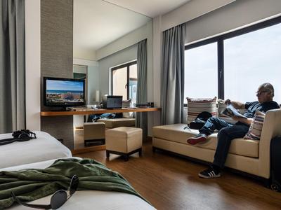 Moderne hotelkamer met zitplek bij raam, bed en werkruimte.