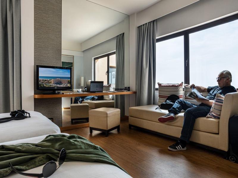 Moderne hotelkamer met zitplek bij raam, bed en werkruimte.