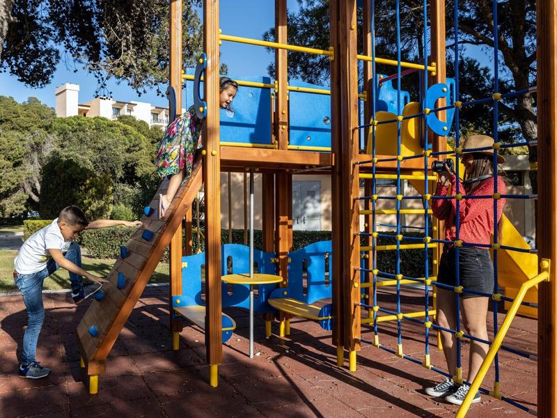 Twee mensen die spelen op een buitenspeelplaats met klimrek en glijbaan.