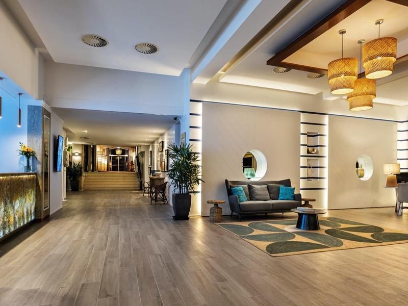 Lichte, moderne hotellobby met houten vloer, zithoek en stijlvolle lampen.