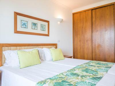 Hell eingerichtetes Hotelzimmer mit Doppelbett, grünen Akzenten und großem Kleiderschrank.