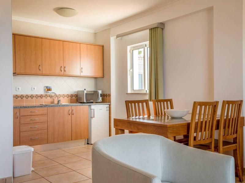 Helle Küche mit Holzschränken und Essbereich mit Holztisch und Stühlen.