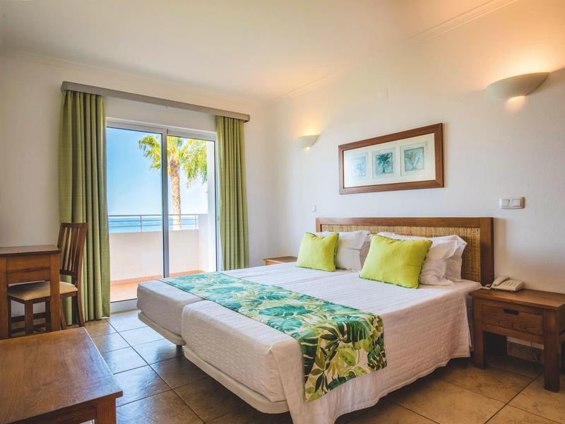 Gemütliches Hotelzimmer mit Doppelbett und Meerblick durch große Fenster