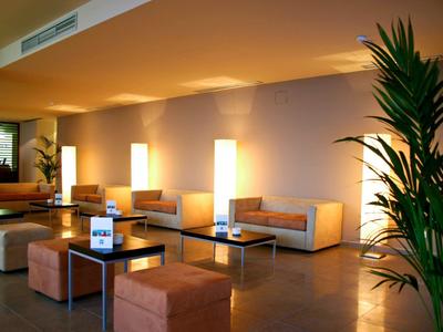 Moderner Barraum mit Theke, hohen Stühlen, Regalen voller Flaschen und Meerblick durch Fenster.