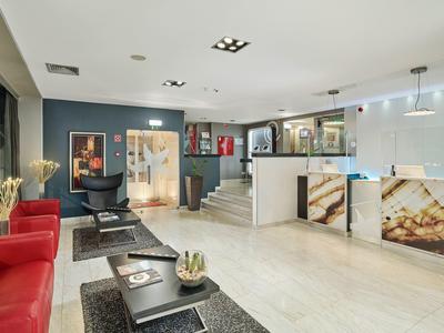 Moderne Lounge mit roten Sesseln, schwarzen Tischen, Aquarien und weißem Thekenbereich.