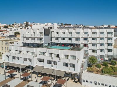 Mehrstöckiges weißes Hotel mit rechteckigen Balkonen unter klarem blauem Himmel.