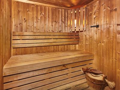 Innensauna aus hellem Holz mit mehrstufigen Sitzbänken und Holzeimer mit Kelle.