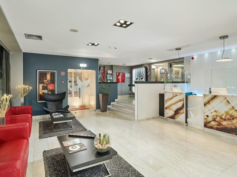 Moderne Lounge mit roten Sesseln, schwarzen Tischen, Aquarien und weißem Thekenbereich.