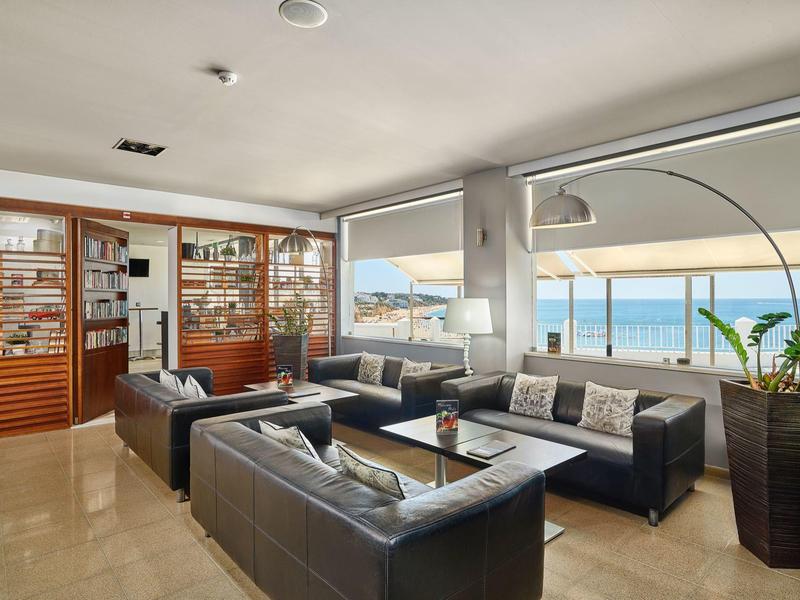 Großzügiges Wohnzimmer mit schwarzen Ledersofas, bodentiefen Fenstern und Meerblick.