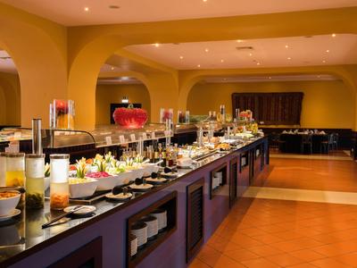 Buffet mit vielfältigen Speisen in einem warm beleuchteten, großzügigen Restaurant mit gelben Wänden.