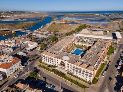 Luftaufnahme einer urbanen Wohnanlage mit Flachdächern, umgeben von Straßen, Wasser und Landschaft.