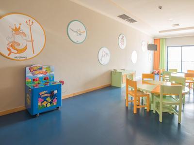 Hell eingerichteter Raum mit bunten Kinderstühlen, Tischen und einer Spielautomatenmaschine.