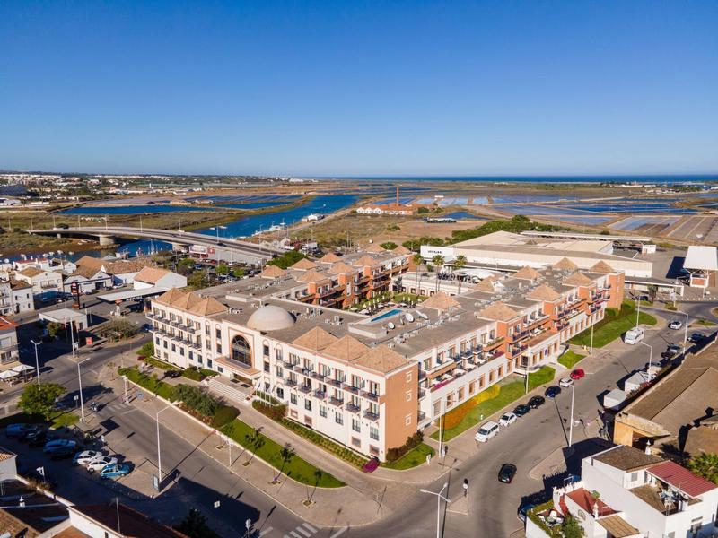 Große Wohnanlage mit roten Dächern nahe Wasser und Infrastruktur unter klarem blauem Himmel.